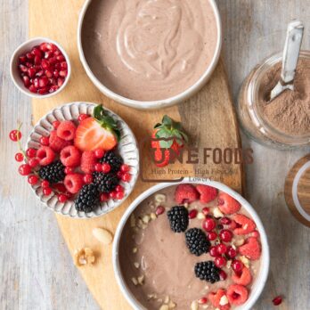 Proteinreicher Schoko-Kollagenpudding mit frischen Beeren und Nüssen, angerichtet auf einem Holzbrett – nährstoffreiches Frühstück oder Snack mit UNE FOODS Schokoladen-Kollagenpulver