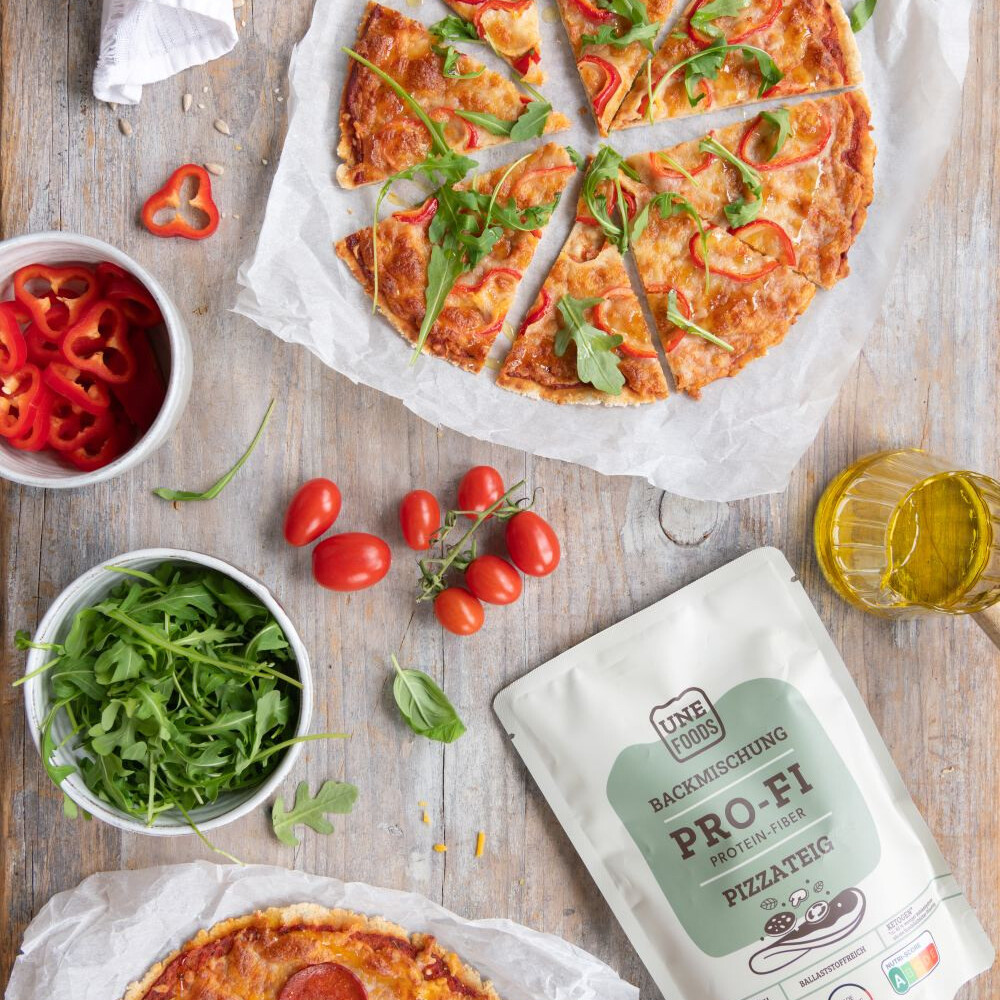 UNE Foods PROFI Pizza Lower Carb fertig gebacken mit Rucola Tomaten und Pizzateig Backmischung