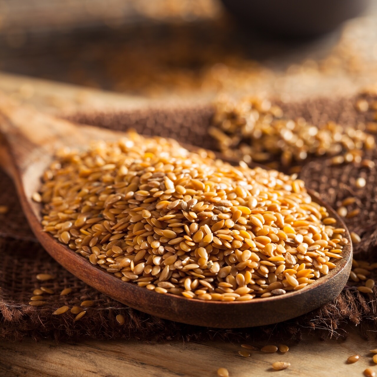 Goldene Bio-Leinsamen in Holzl&ouml;ffel auf rustikalem Untergrund, nat&uuml;rliche Zutat f&uuml;r Protein-Fiber Backmischungen